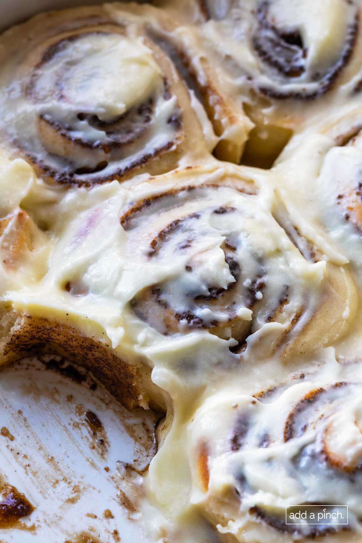 Closeup of frosted homemade cinnamon rolls with one removed from the pan.