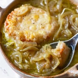 Bowl of French Onion Soup with a spoon filled ready for a bite.