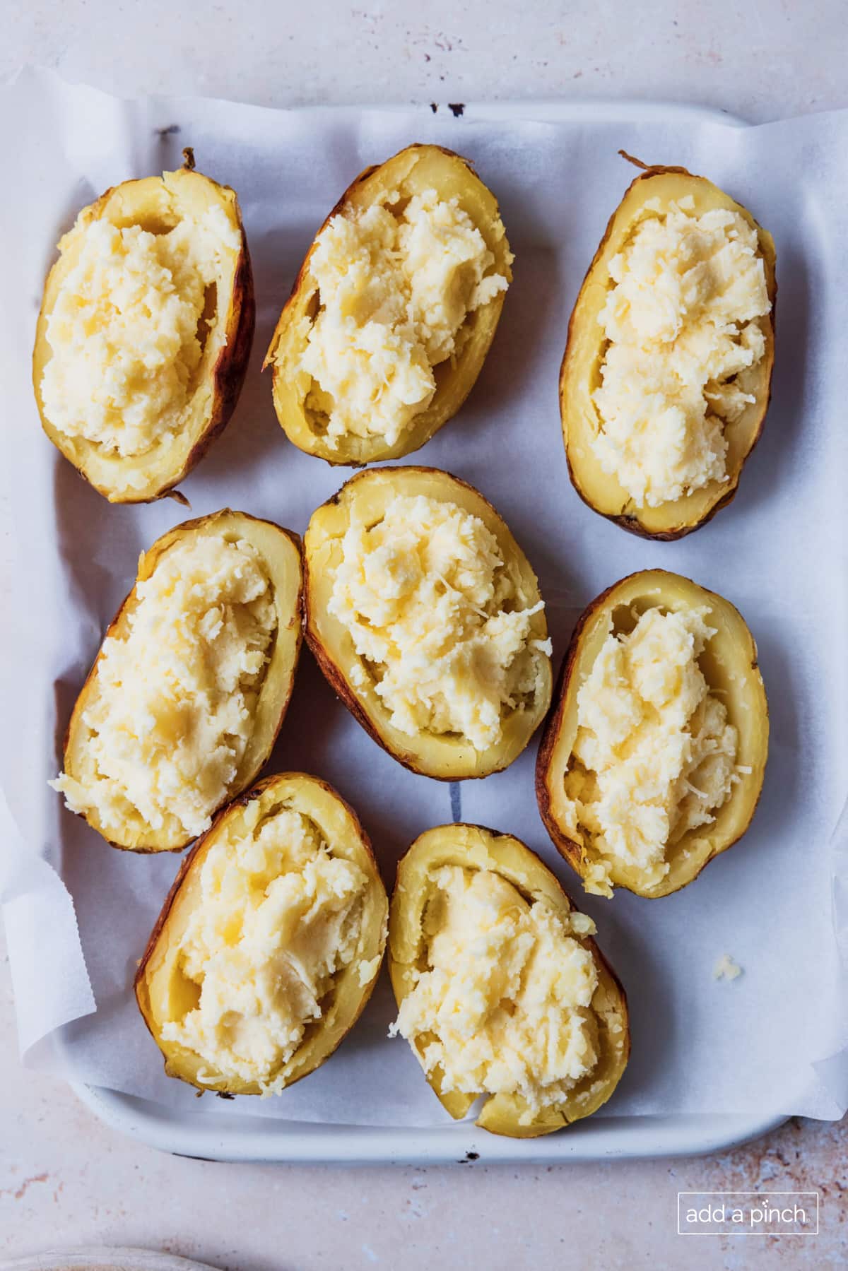 Potatoes have creamy mashed potato filling added back into the scooped skins and are ready to garnish and bake.