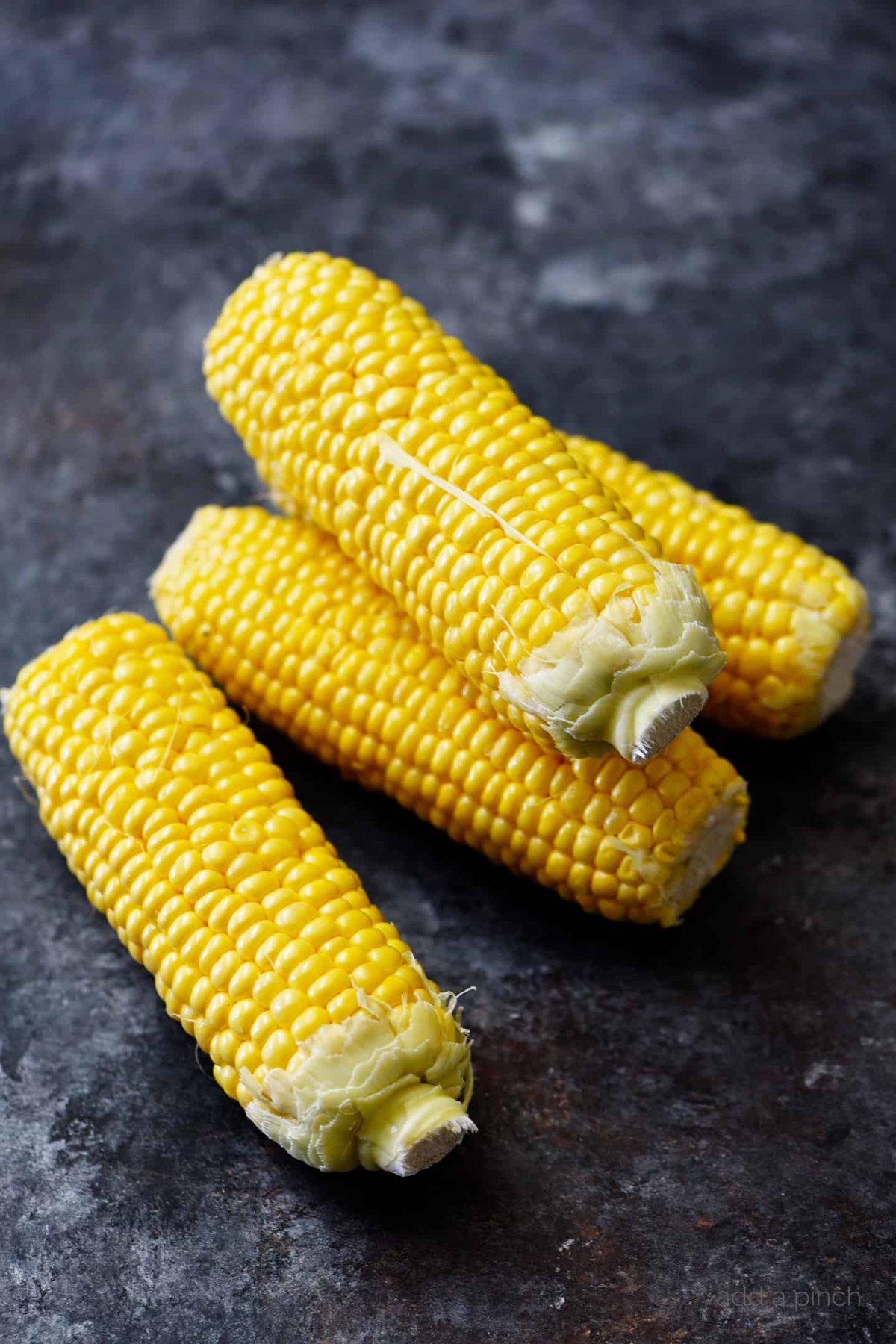 Photo of clean corn on the cobb on a dark background.
