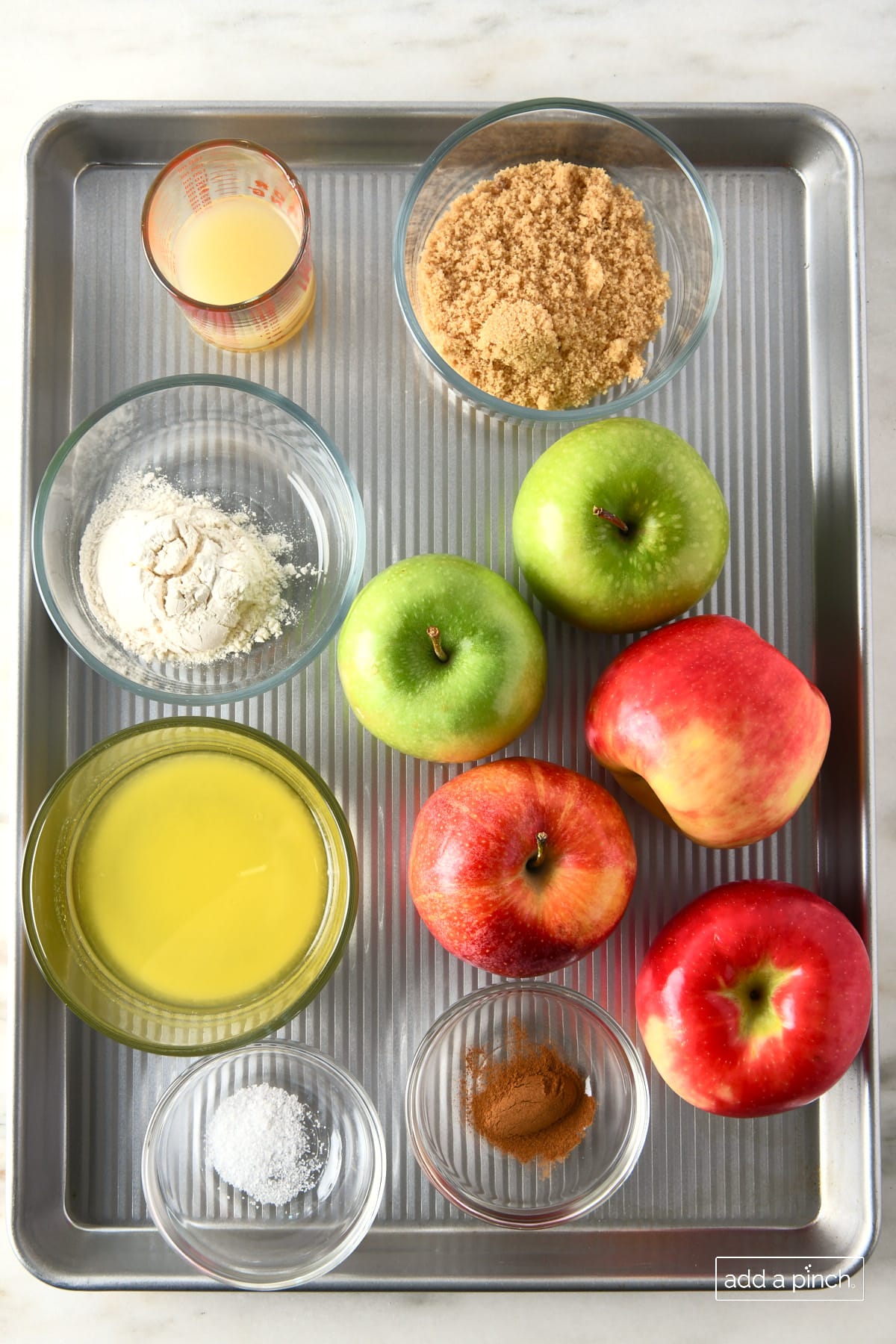 Apples, brown sugar, butter, flour, lemon juice and cinnamon on a baking pan.