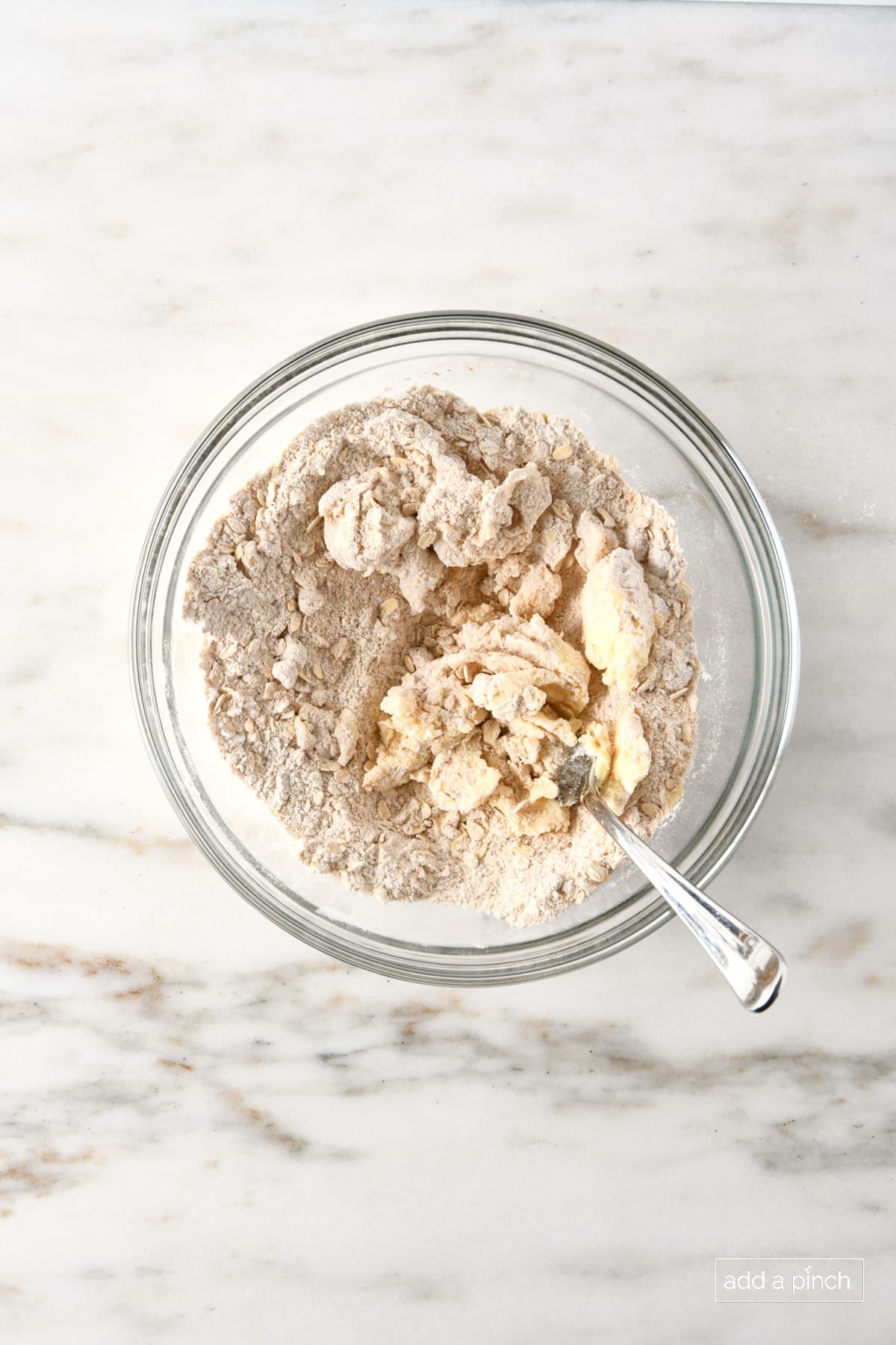 Butter is combined with dry ingredients for oat streusel topping for apple crisp.