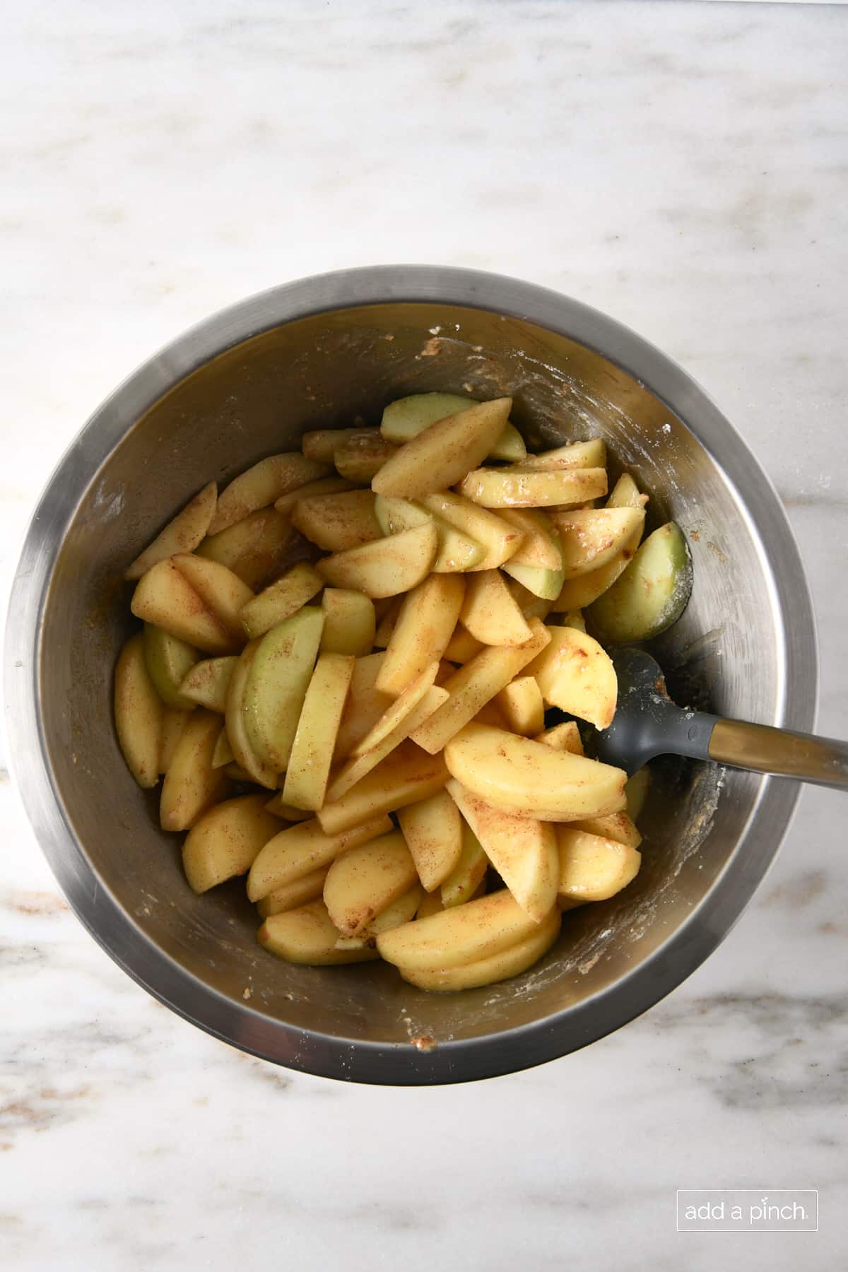 Mixing bowl holds apple crisp filling after all the ingredients are mixed with the sliced apples.