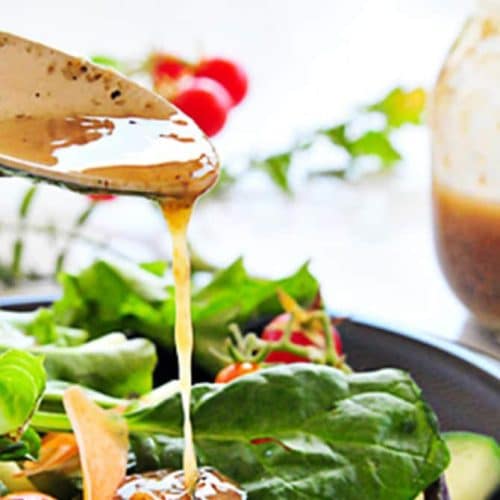 Image of buttermilk dressing being spooned onto a plate of green salad with tomatoes, cheese, and avocado.