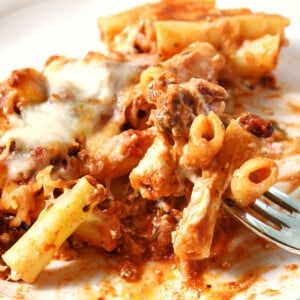 Baked ziti on a white plate with a bite on a fork.