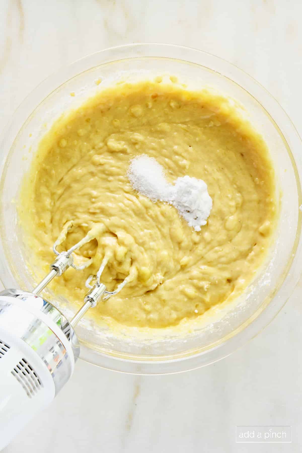 Baking soda and baking powder added to muffin batter in a glass bowl.