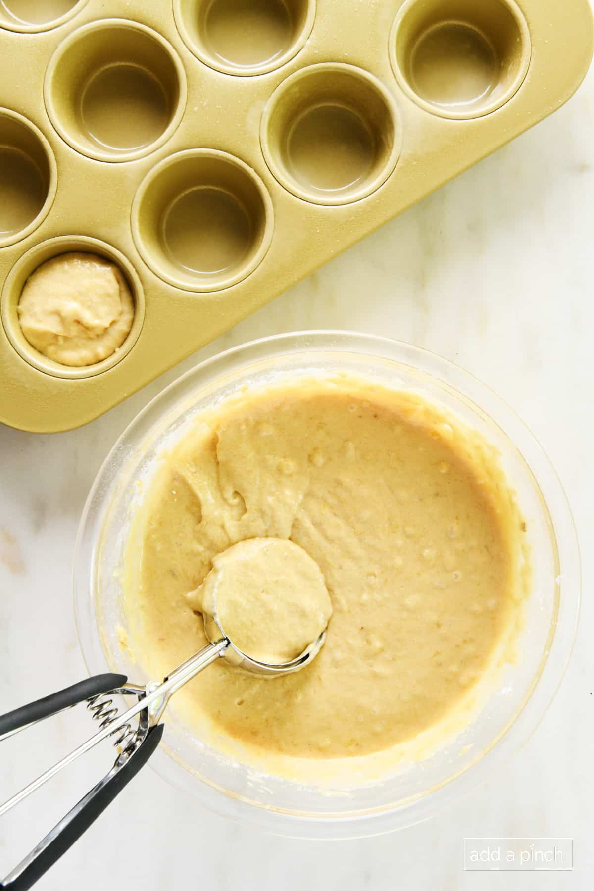 Scoop of banana muffin batter being added to a muffin pan.