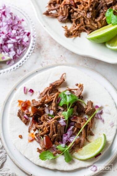 Barbacoa on soft tortilla with lime, cilantro and red onion.