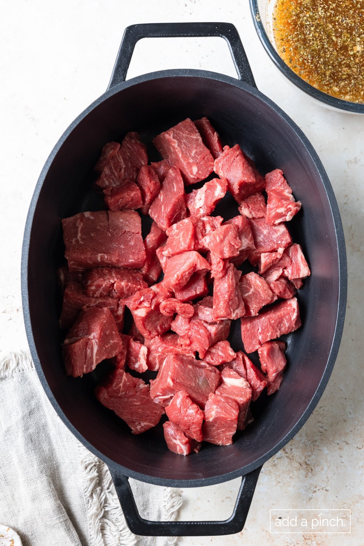 Photograph of beef cut into cubes placed in slow cooker ready to be cooked.