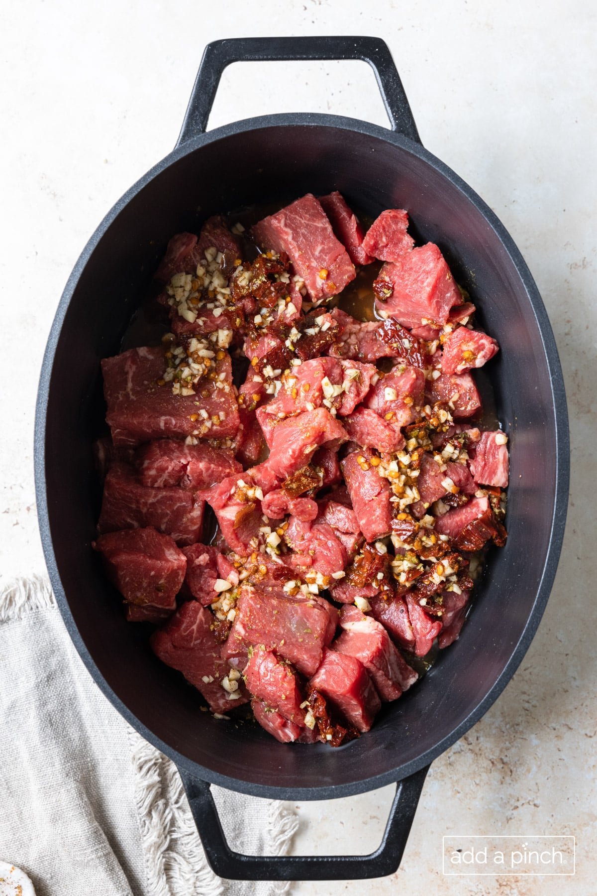 Beef with sauce and seasonings in a slow cooker insert ready to cook.