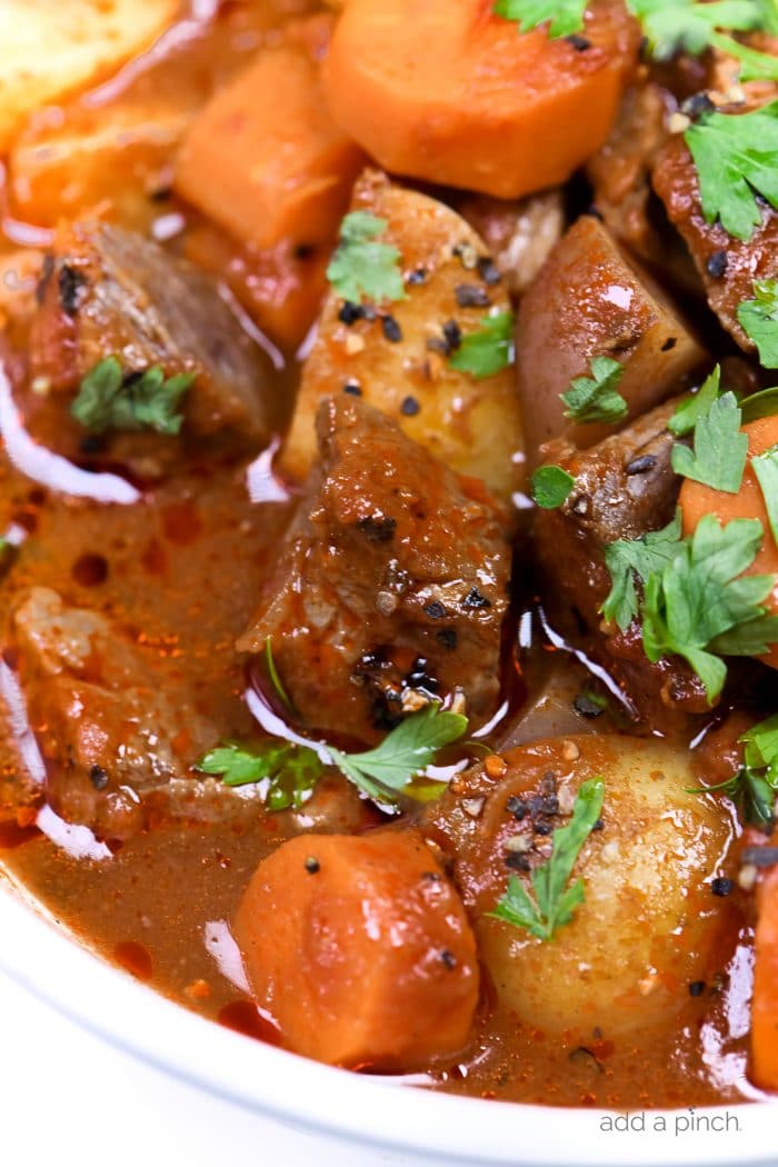 Photograph of homemade beef stew in a white bowl. // addapinch.com