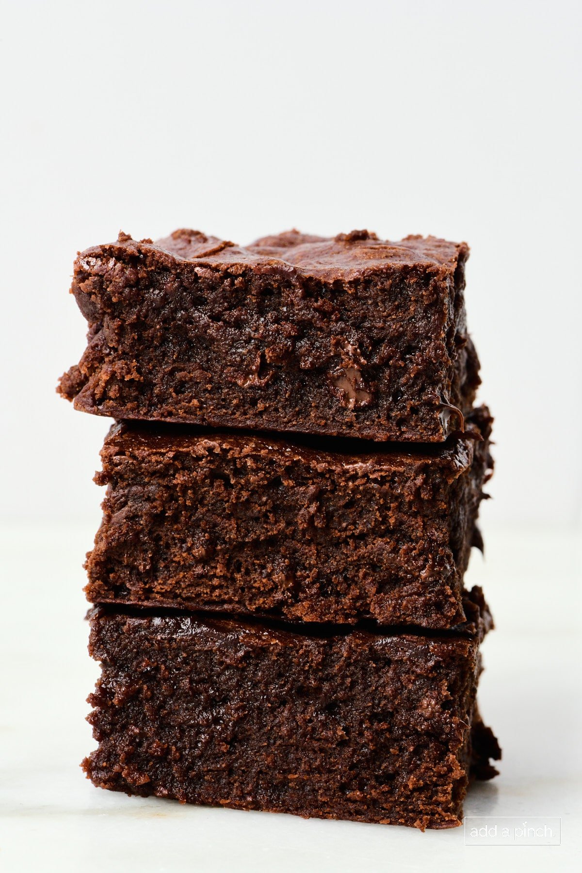 Stack of the gooey, chocolatey brownies on a marble countertop.
