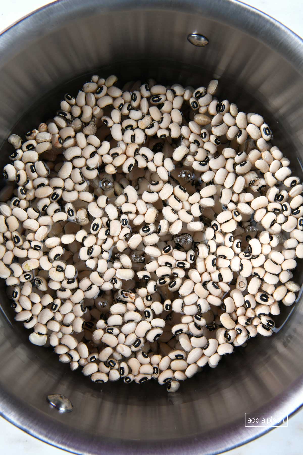 Dried peas soaking in water in a large pot.