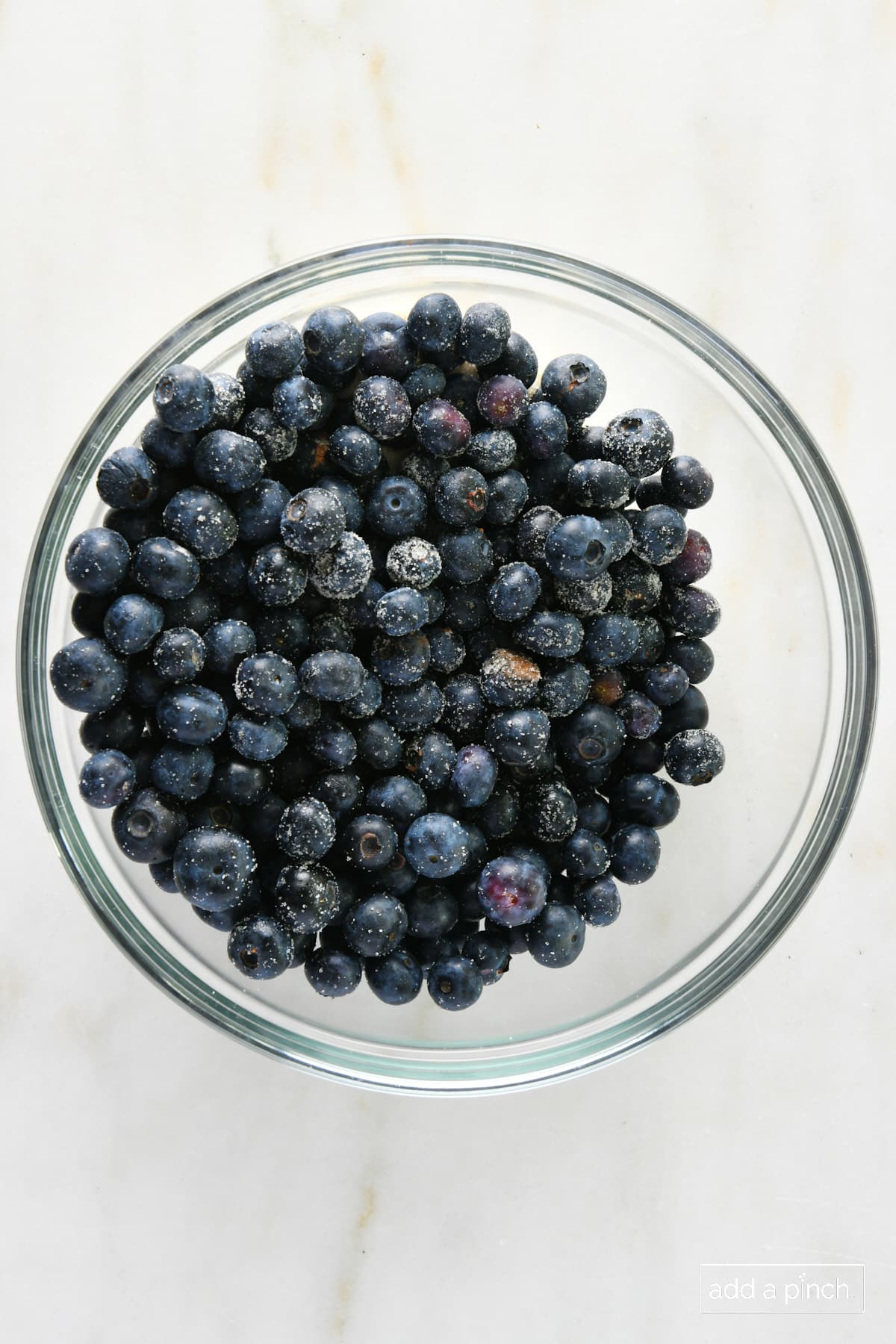 Blueberries tossed in sugar in a glass bowl