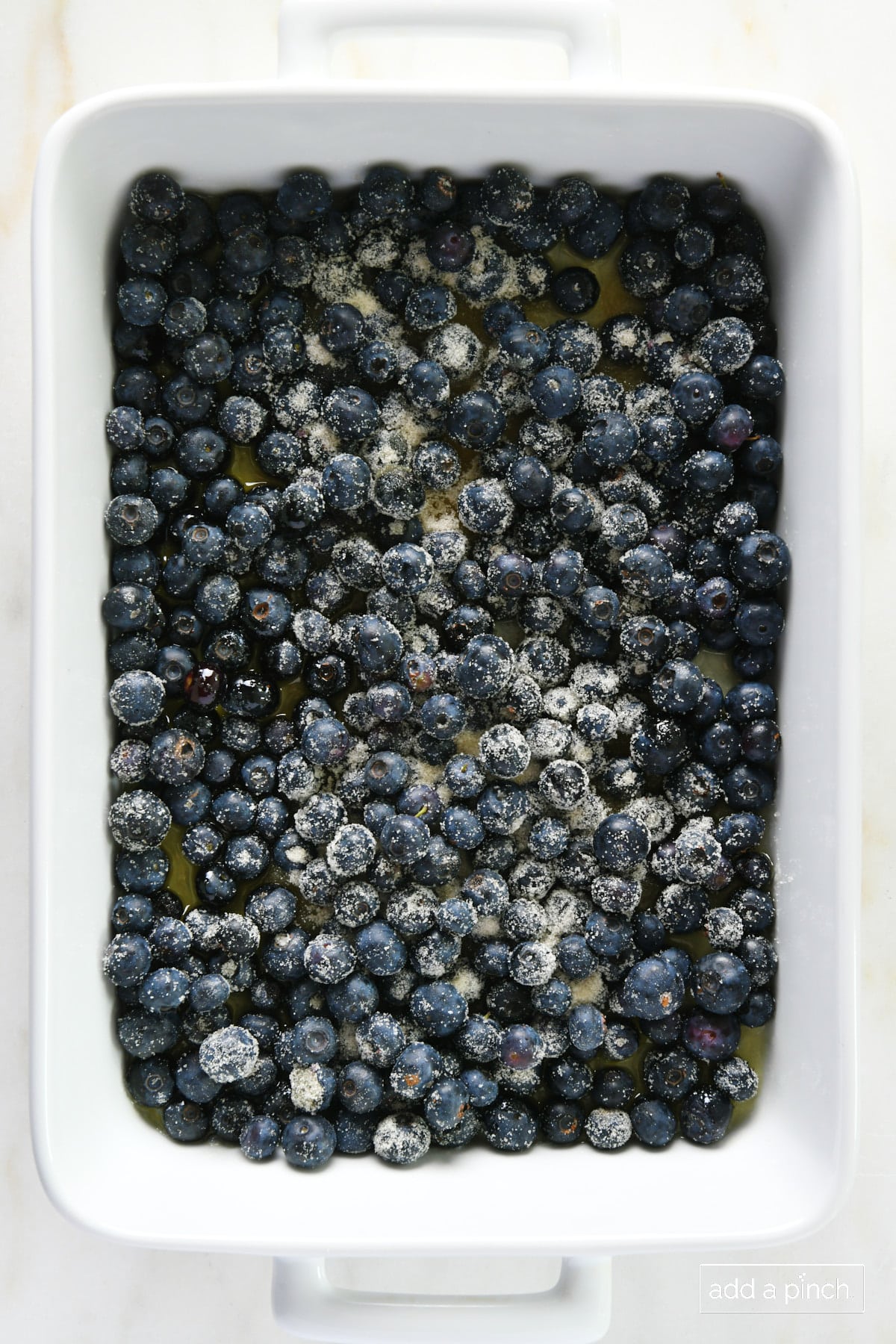 Sugared blueberries in a white baking dish.