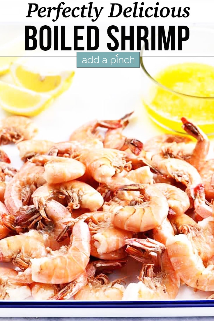 Boiled Shrimp with lemon slices and drawn butter on a white enamel serving tray - with text - addapinch.com