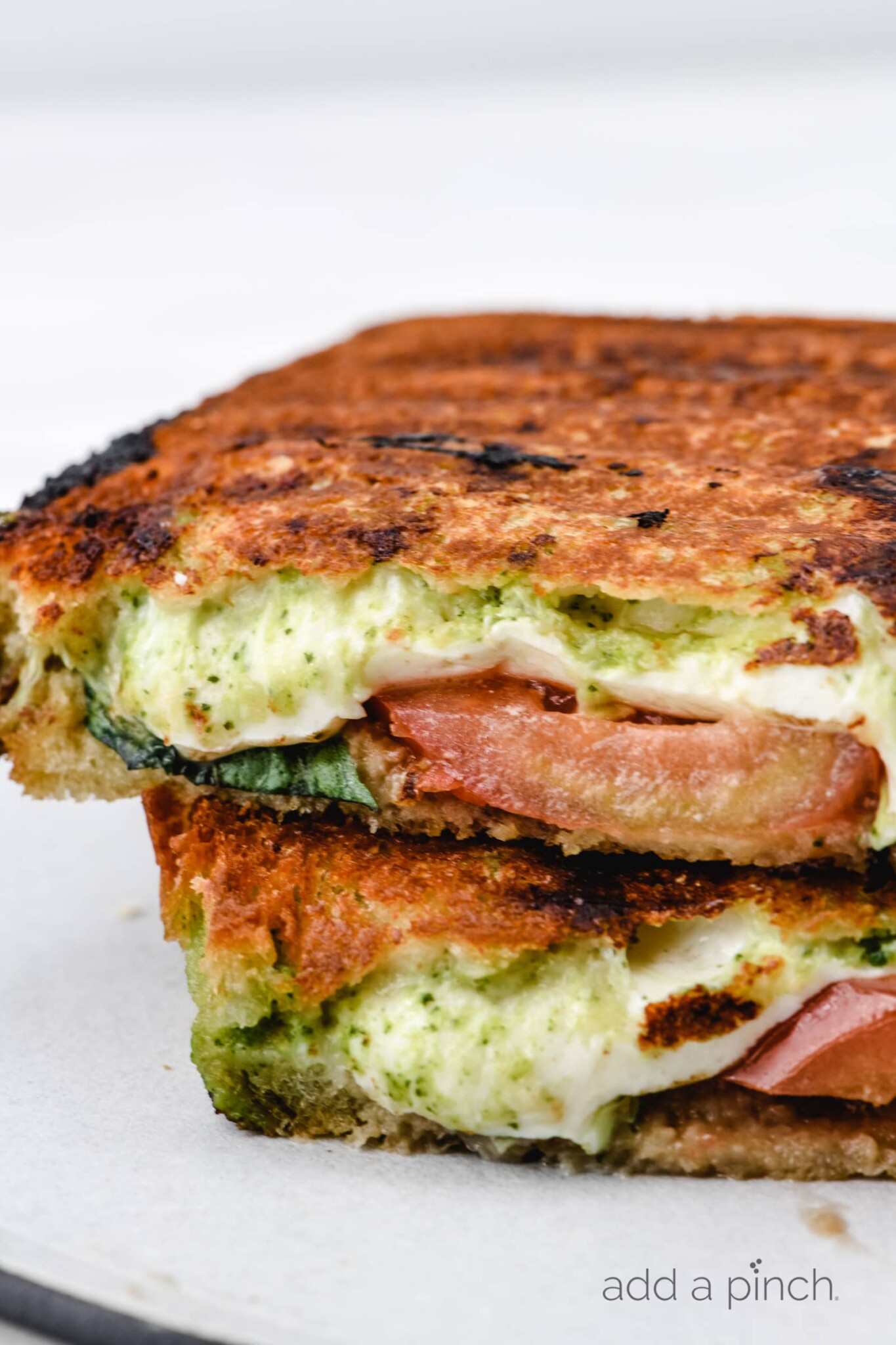 Closeup of caprese grilled cheese sandwich sliced in half // addapinch.com