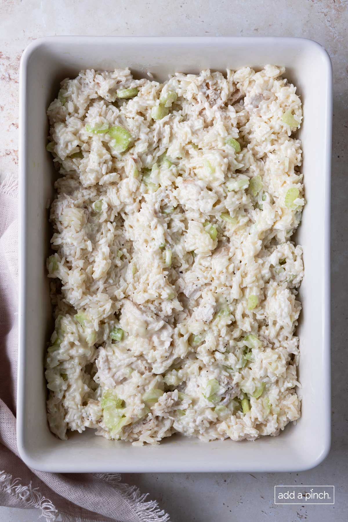 Chicken and rice casserole mixture in a white baking dish ready to be baked.