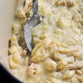 Photo of chicken and dumplings in a Dutch oven with a serving spoon.