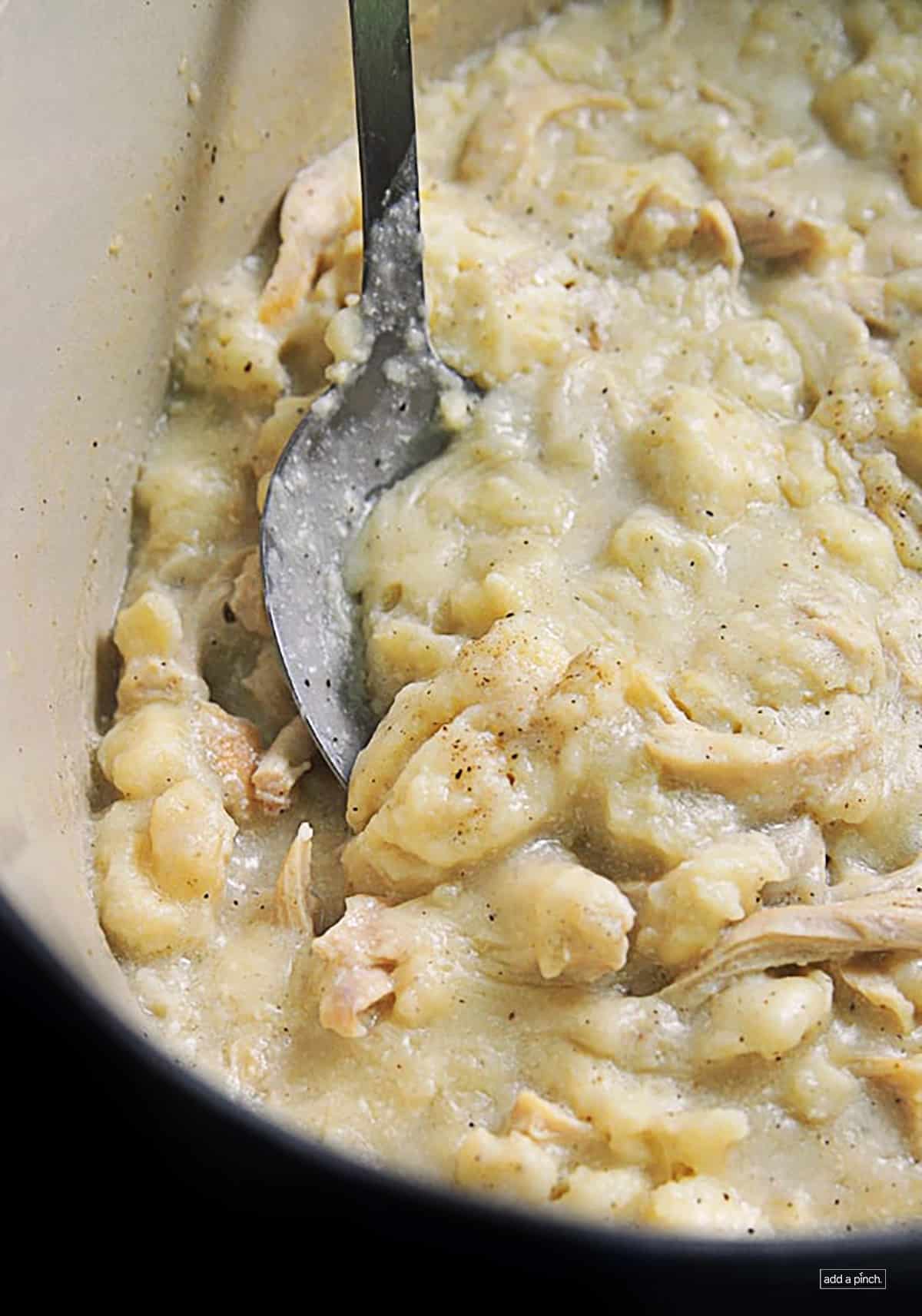 Photo of dutch oven filled with homemade chicken and dumplings with fluffy made from scratch dumplings.