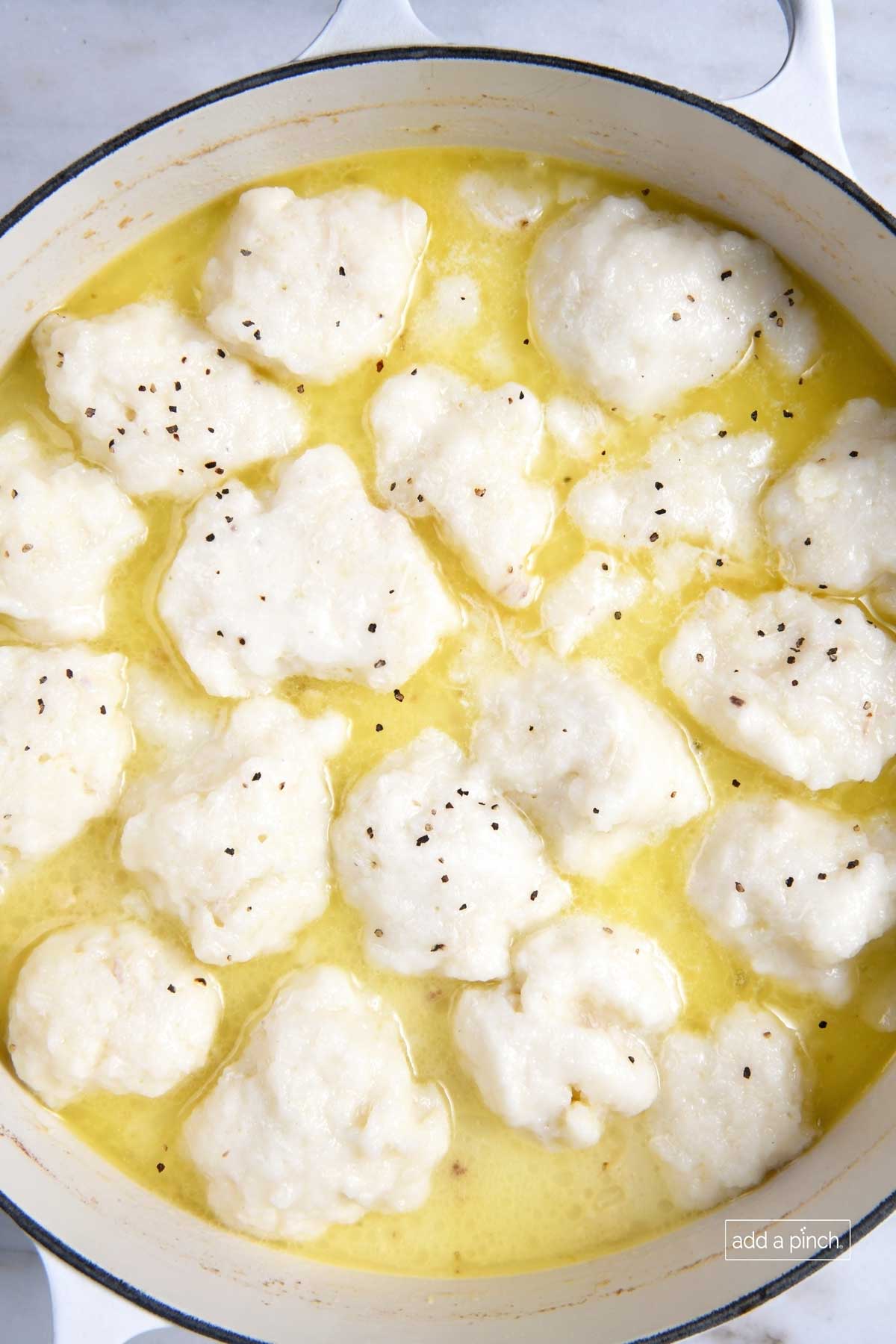 Photograph of chicken and dumplings simmering in a Dutch oven.