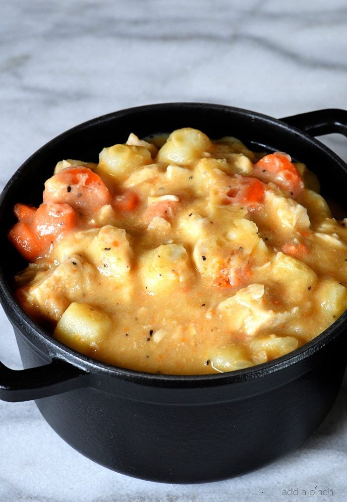 Chicken pot pie ingredients - carrots, potatoes, chicken all in a thick chicken stock broth - in a black dutch oven. 