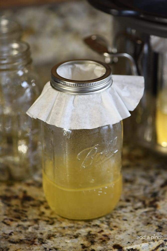Chicken stock in a ball canning jar with a coffee filter on top with ring lid.