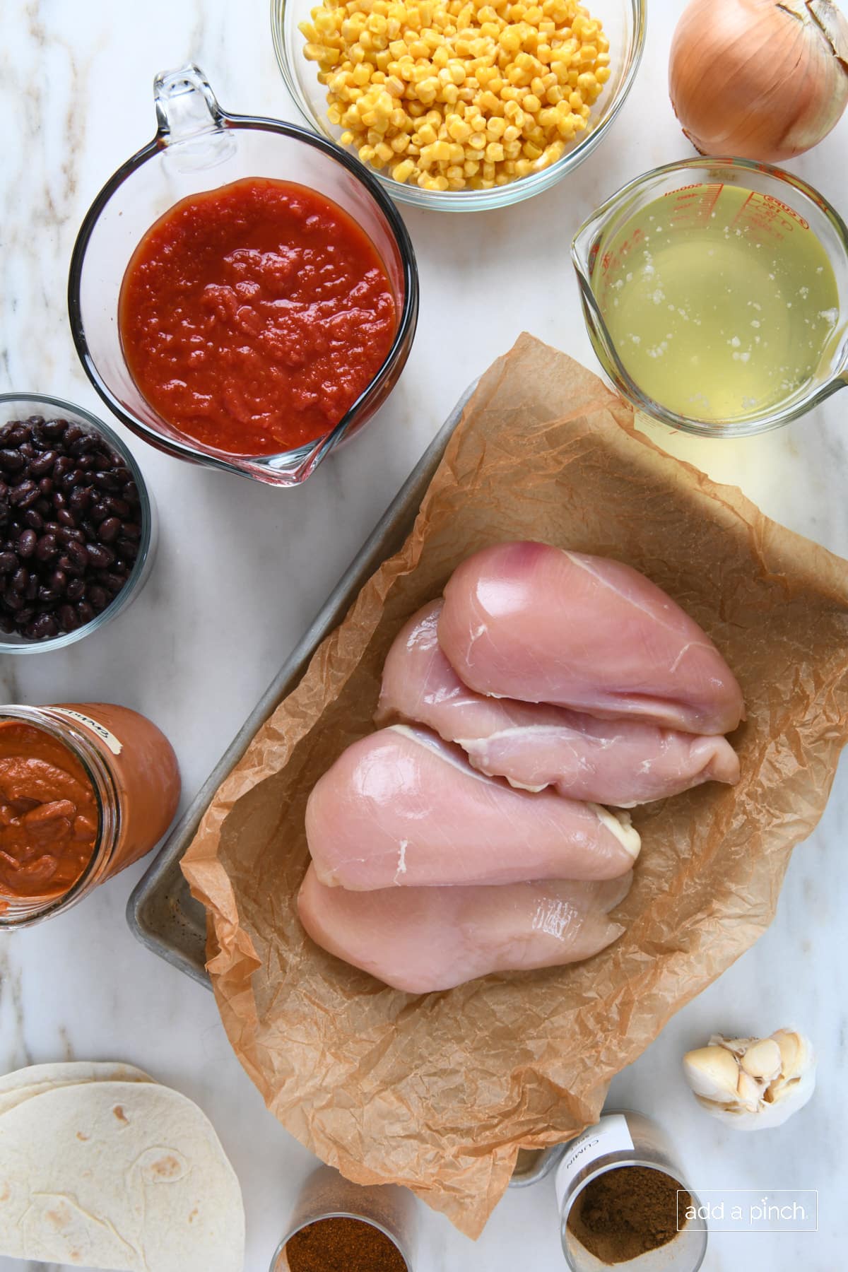 Chicken breasts, chicken stock, enchilada sauce, crushed tomatoes, black beans, corn, onion, garlic cloves, spices and tortillas for chicken tortilla soup.