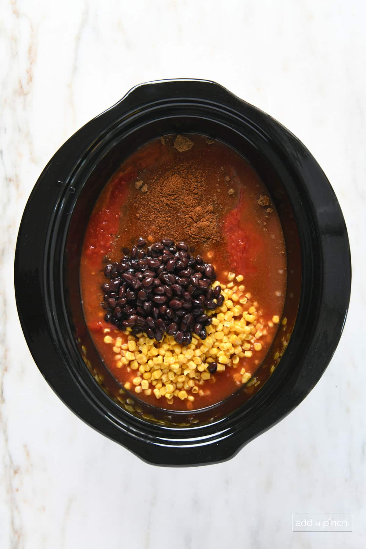 Stoneware pot with corn, beans, spices, tomatoes and other ingredients for Chicken Tortilla Soup.