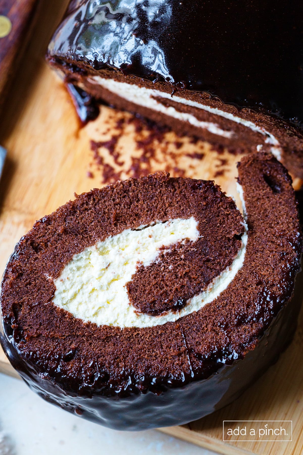 Slice of chocolate cake roll on a showing the sweetened whipped cream filling and the ganache frosting.