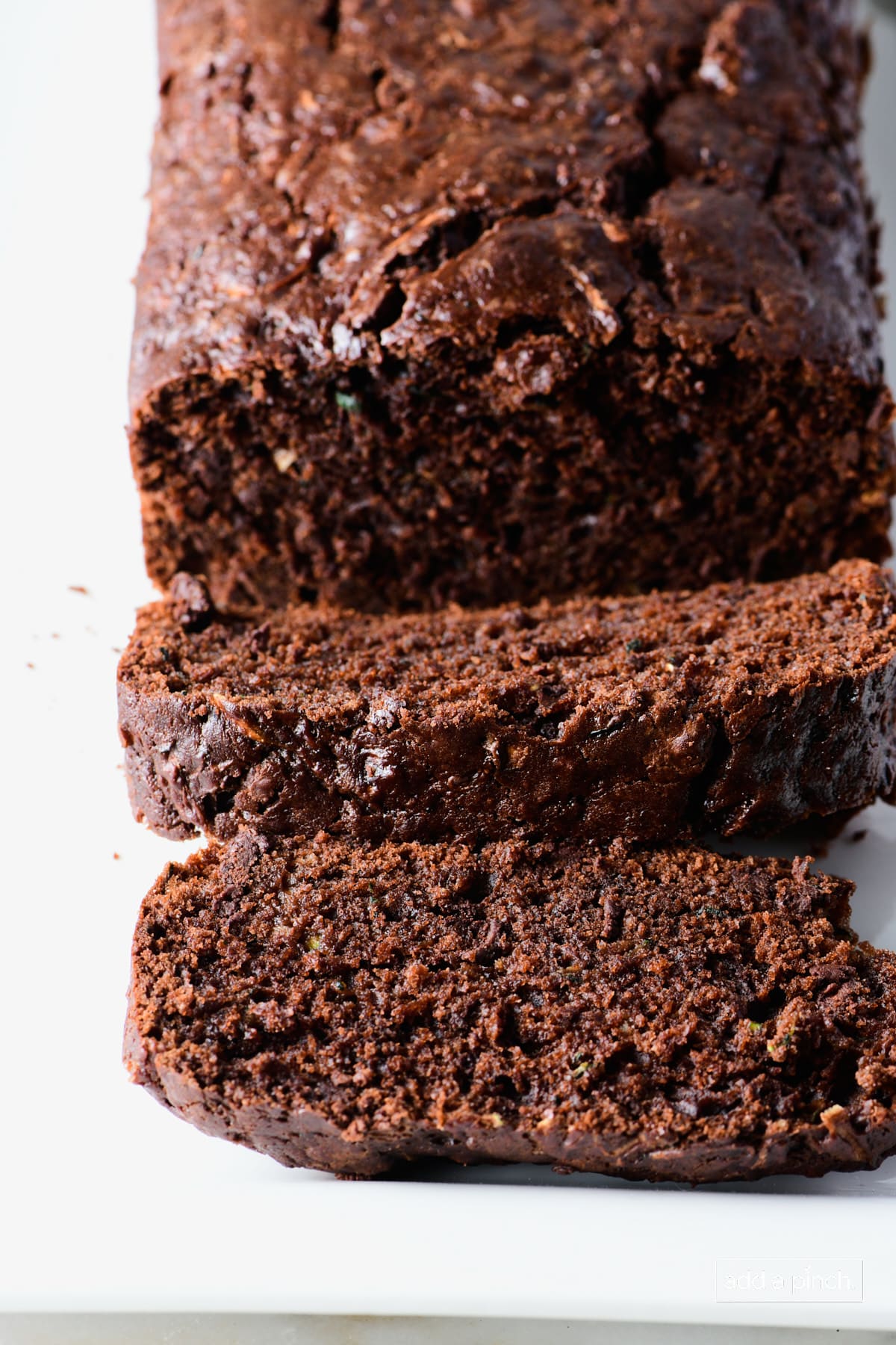Photo of chocolate zucchini bread slices on a white platter.