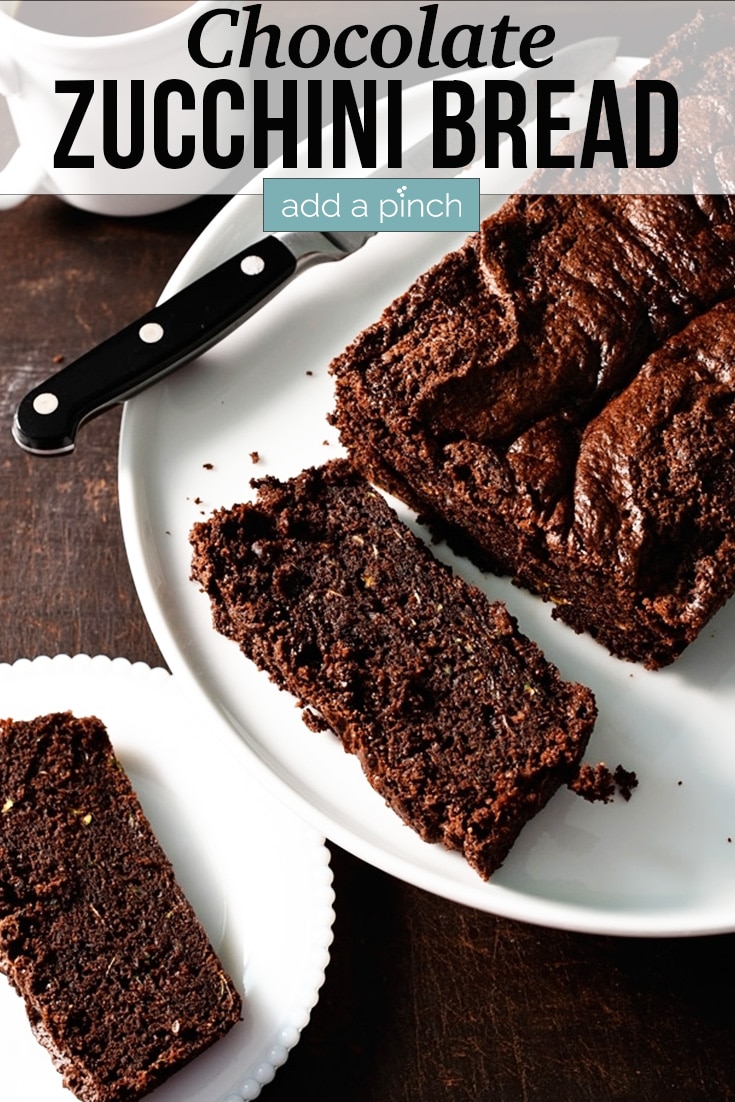 Chocolate Zucchini Bread on white platter with two pieces sliced off beside cup of coffee - with text - addapinch.com