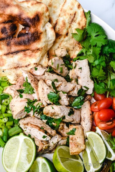 Cilantro Lime Chicken surrounded by limes, cilantro, tomatoes and a grilled tortilla.