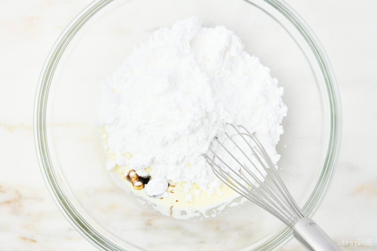 Vanilla glaze ingredients in a glass bowl with a whisk.