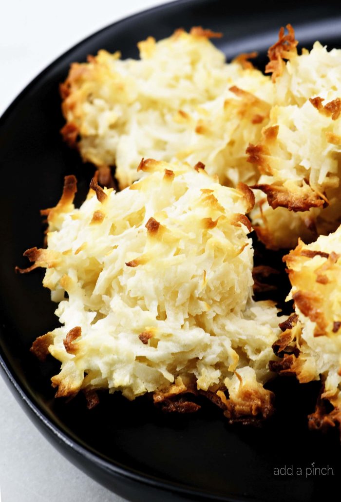 Golden browned coconut macaroons on a black plate.