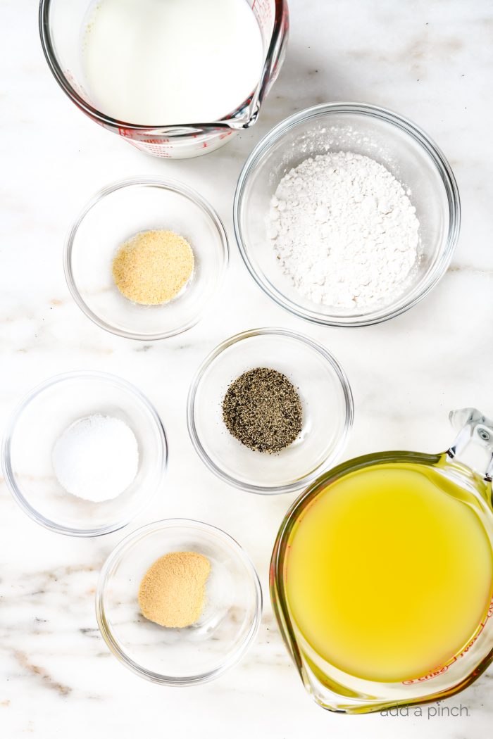 Ingredients to make cream of chicken soup in individual bowls on a marble countertop.