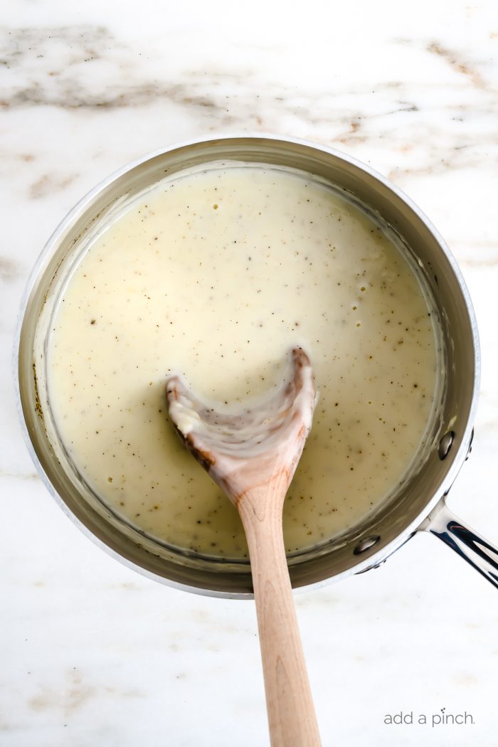 Condensed cream of chicken soup in a saucepan with a wooden spoon. 