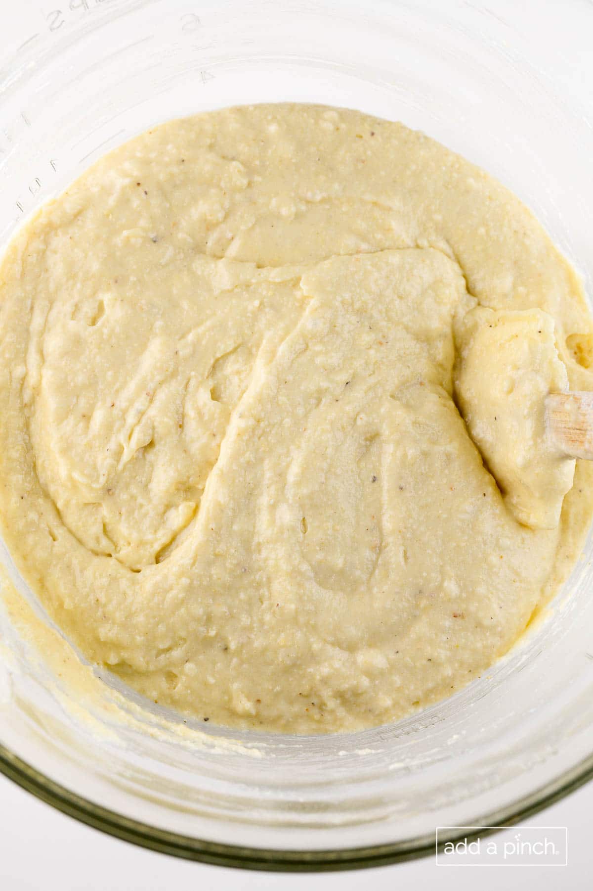 Photograph of cornbread muffin batter in a clear bowl. 