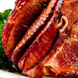 Photograph of cooked ham on a white platter.