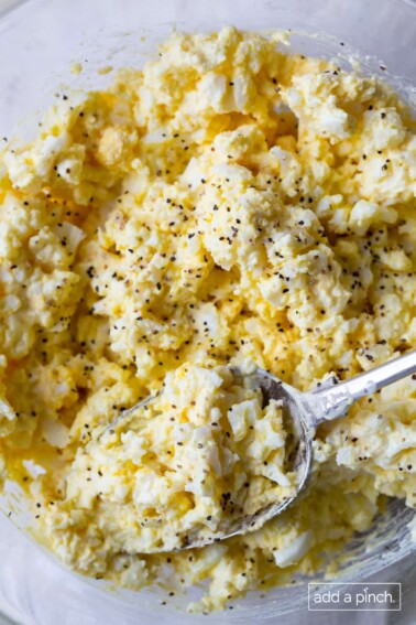 Classic egg salad in a bowl with a silver spoon.