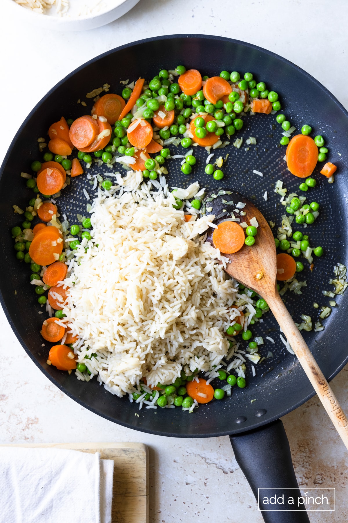 Photo of rice, peas and carrots for fried rice in a skillet.