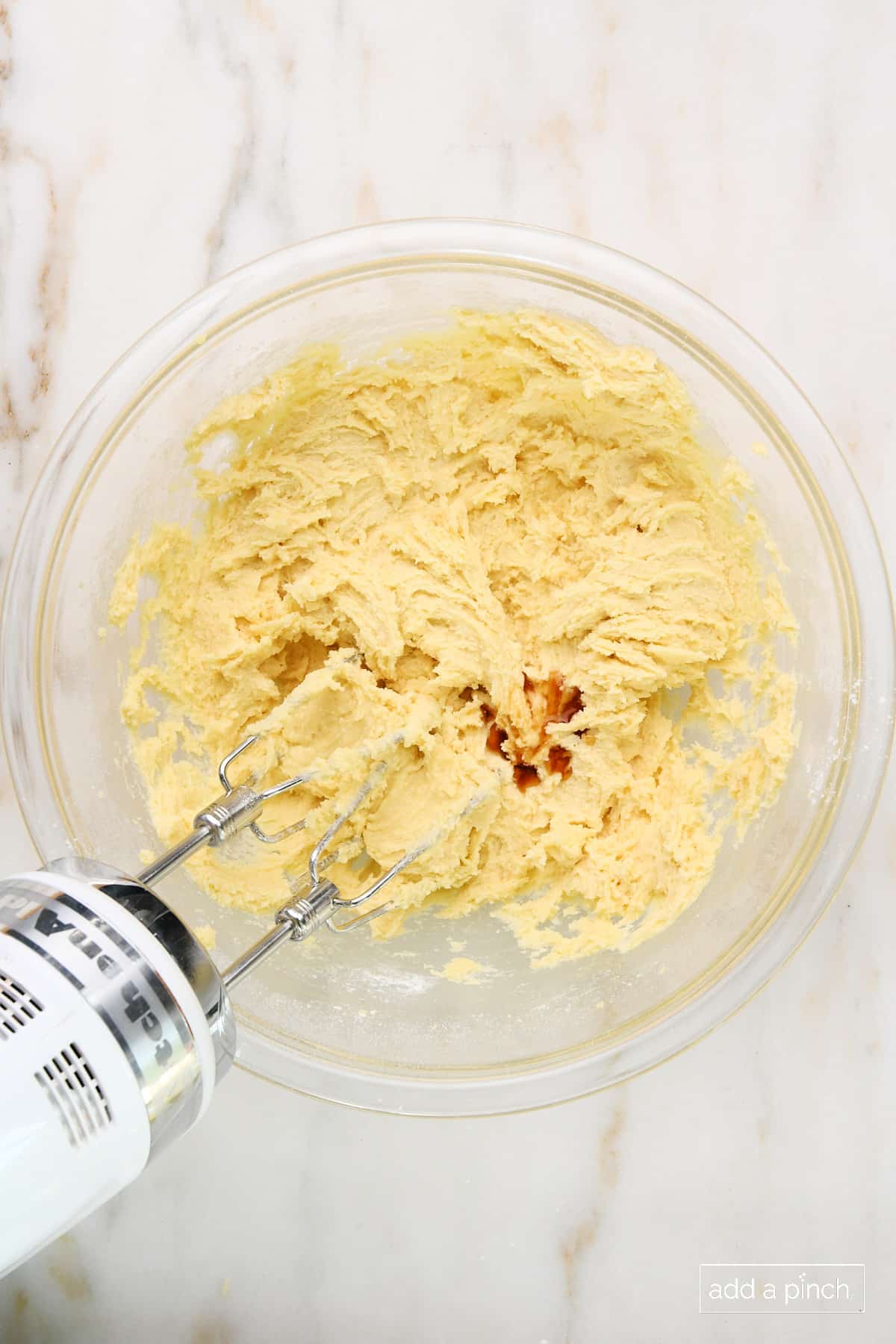 Vanilla extract added to cookie dough mixture in glass mixing bowl