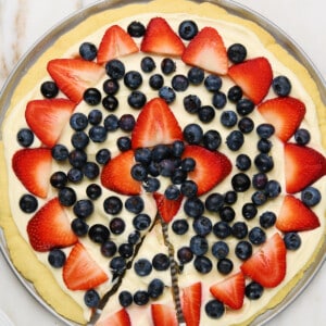 Photo of fruit pizza with a slice for serving.