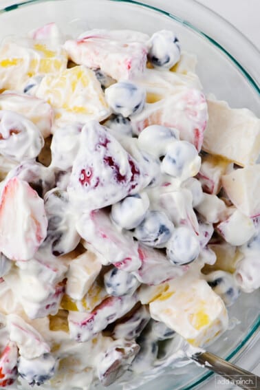 Fruit salad with a creamy dressing in a glass bowl.