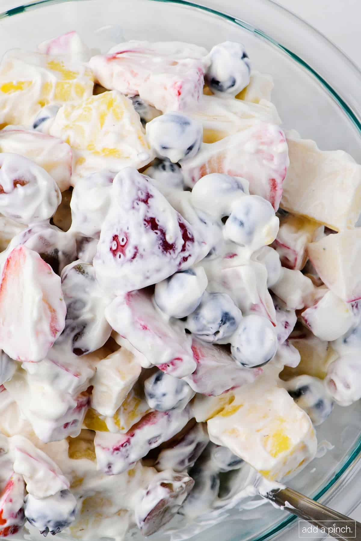 Fruit salad with a creamy yogurt dressing in a glass bowl.