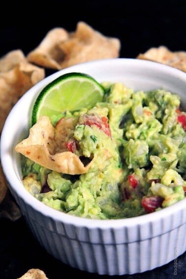 Guacamole in a white bowl with a slice of lime.