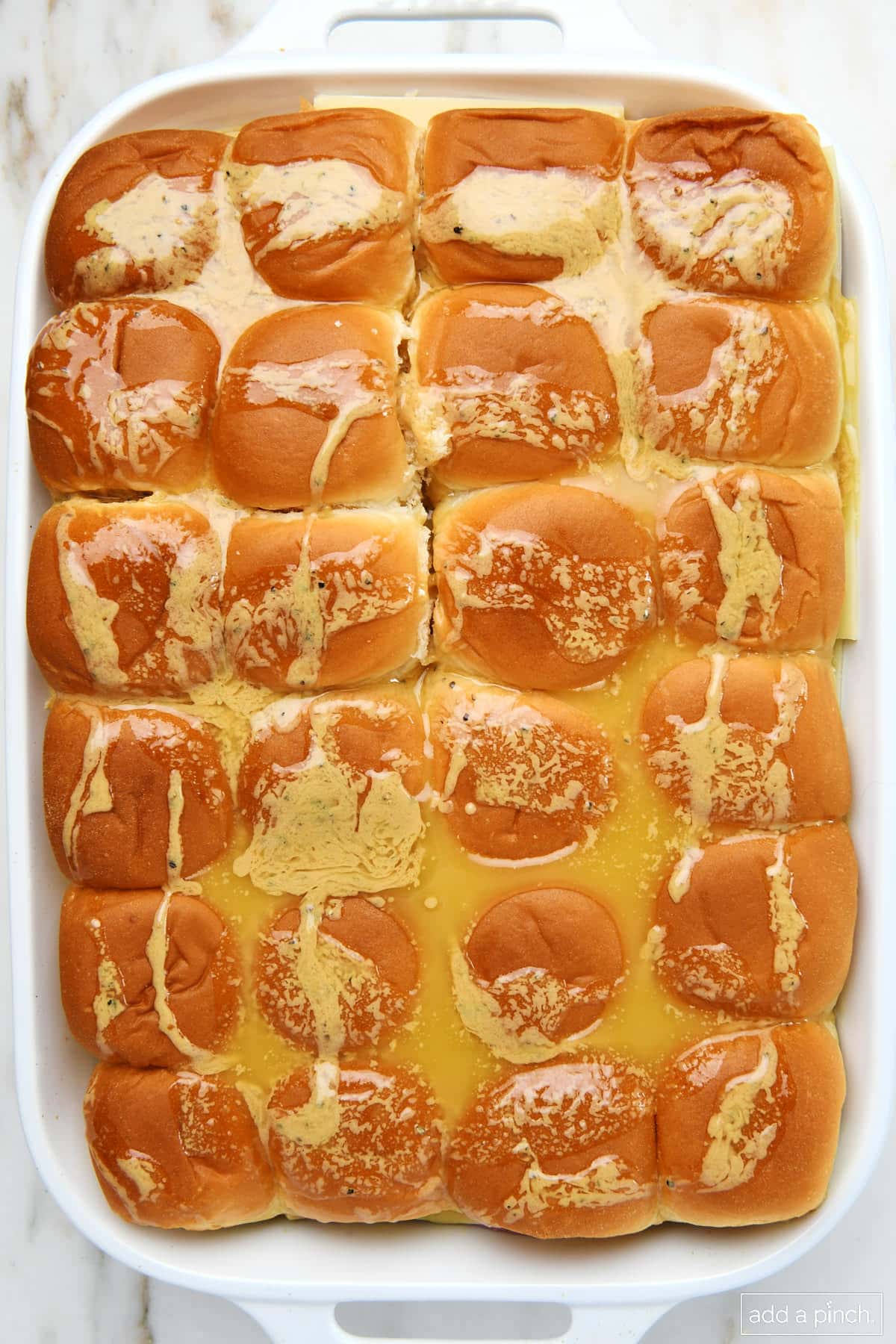 Buttery spread poured over the top of rolls in a 9x13 baking dish.