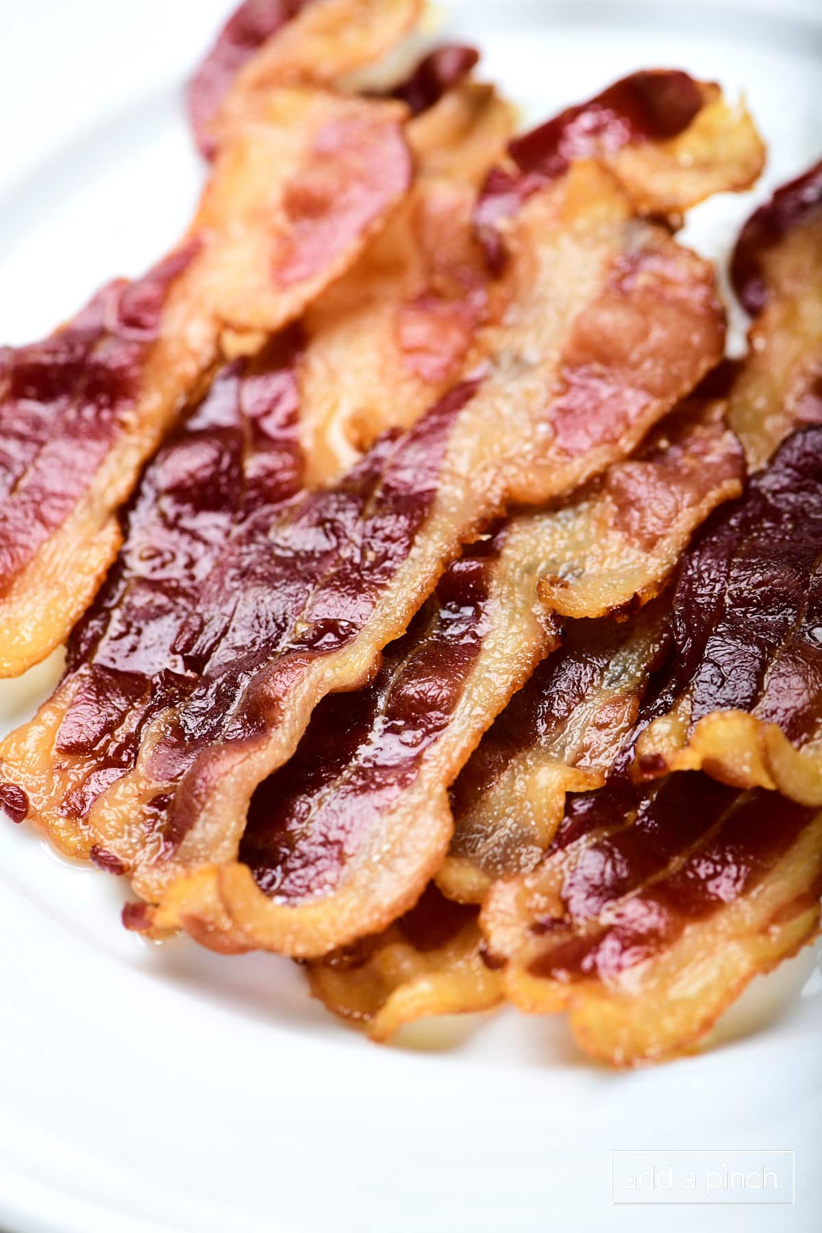 Cooked bacon on a white plate.