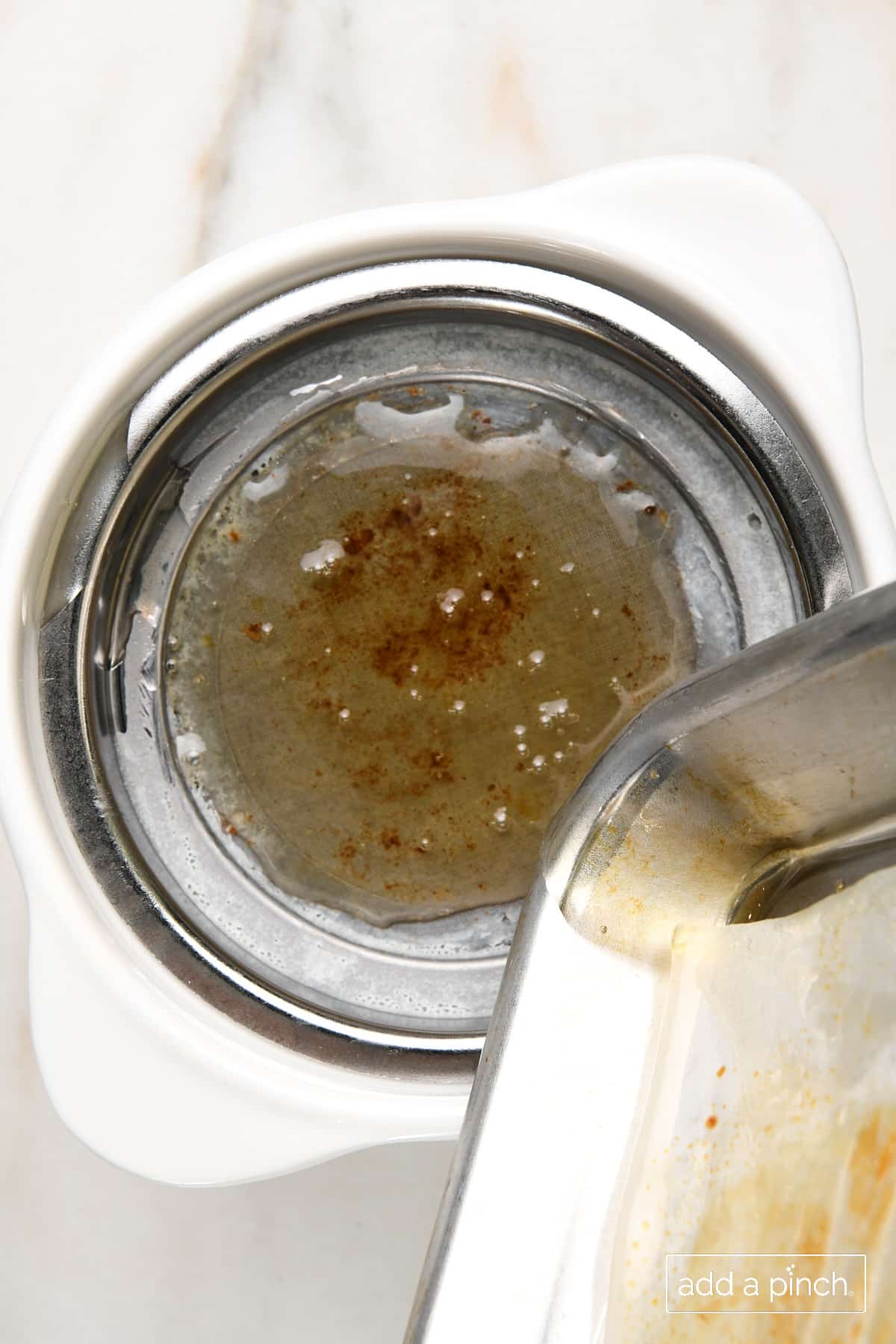 Photo of bacon grease being poured into a bacon grease container to use later. 