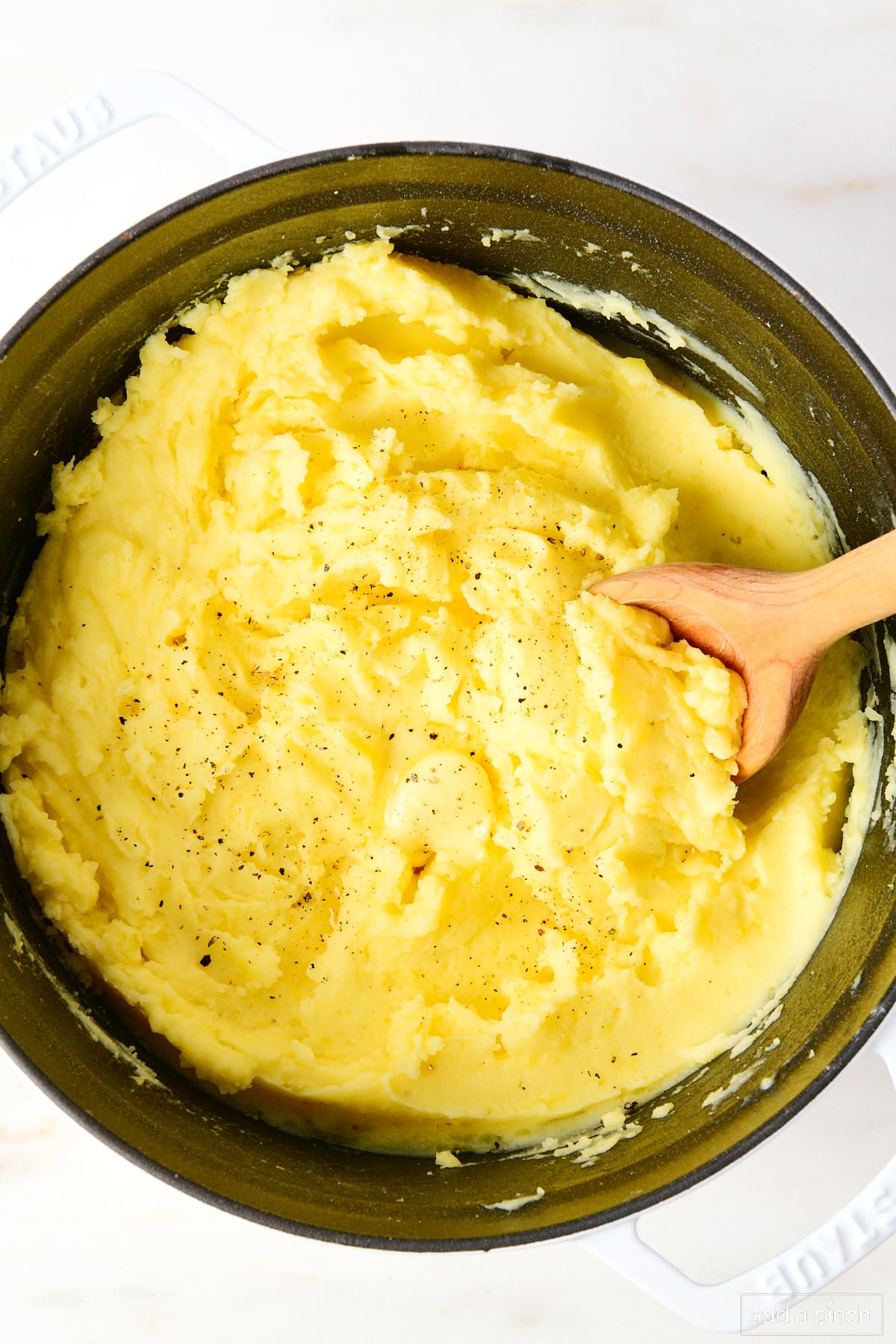 Photo of mashed potatoes in black bowl on white background.